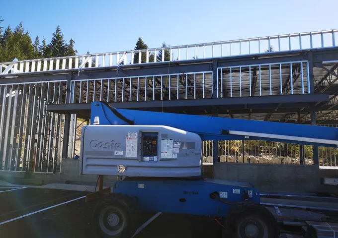 Steel framing structure under construction with Genie boom lift on a BC job site — JEGO Walls & Ceilings