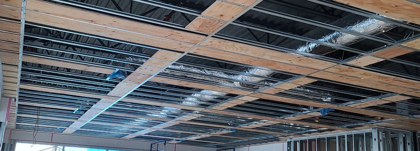 Steel stud wall framing against a golden sunset on a Vancouver Island commercial job site — JEGO Walls & Ceilings